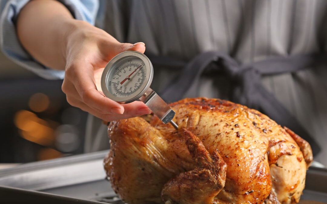 woman using a meat thermometer to check temp on turkey.